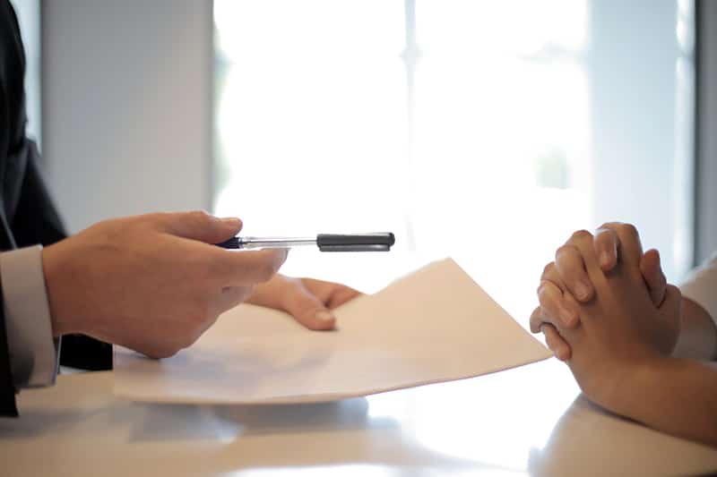 Downpayment and closing cost assistance (man passing paper in meeting)