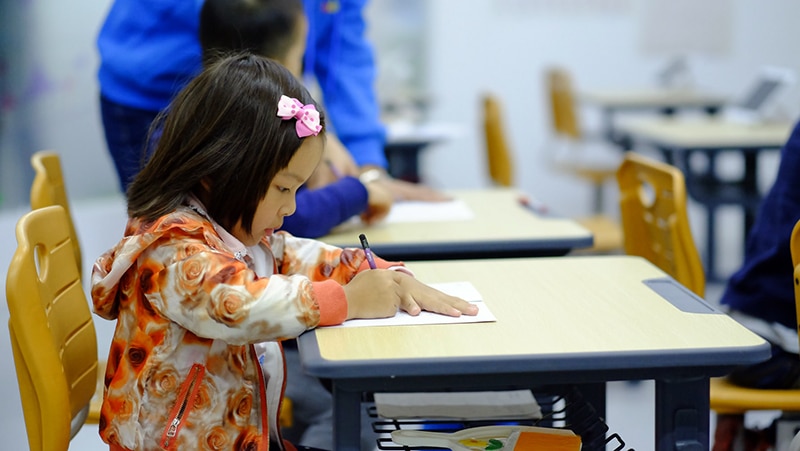 Housing and educational outcomes (little girl writing at school desk)