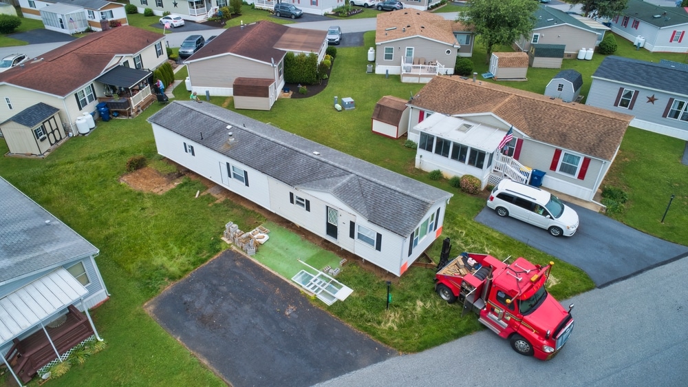 Image of manufactured home being removed from its foundation and pulled by a truck
